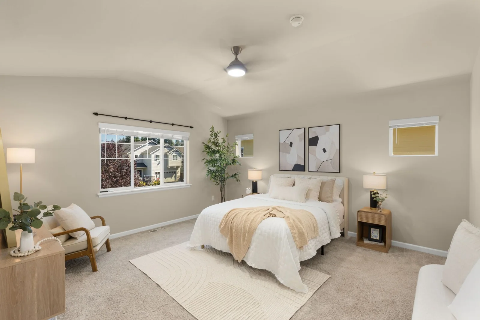 Bedroom with neutral bedding, a textured throw, framed artwork, and a reading chair