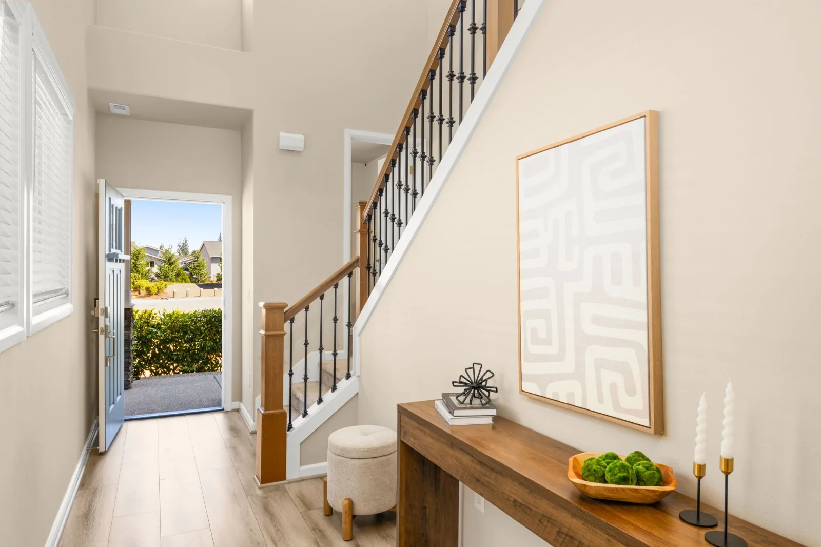 Bright entry hall with a wood console, framed artwork, and a staircase