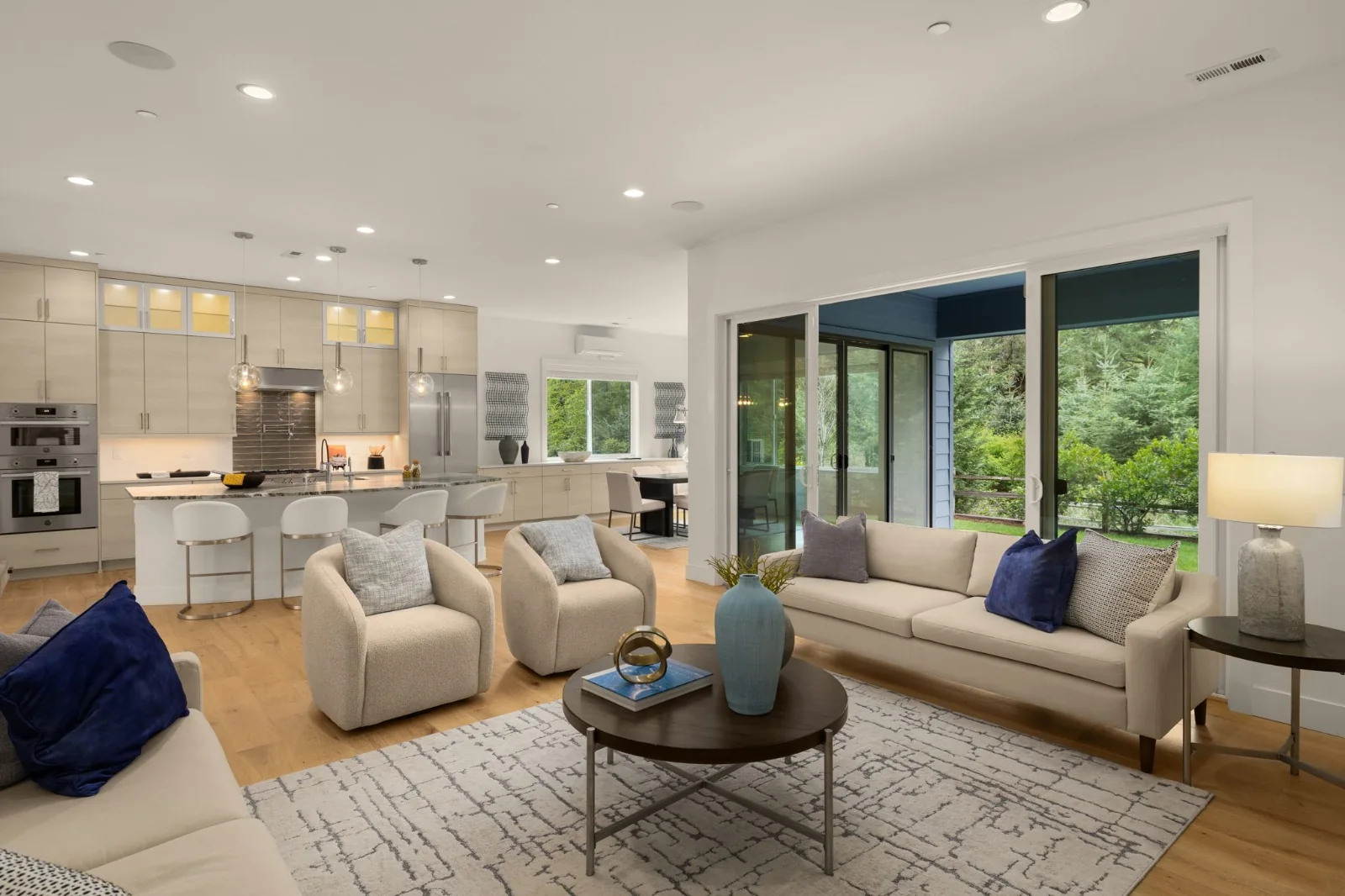 Living room with cream sofas, blue cushions, a coffee table, and garden-facing windows