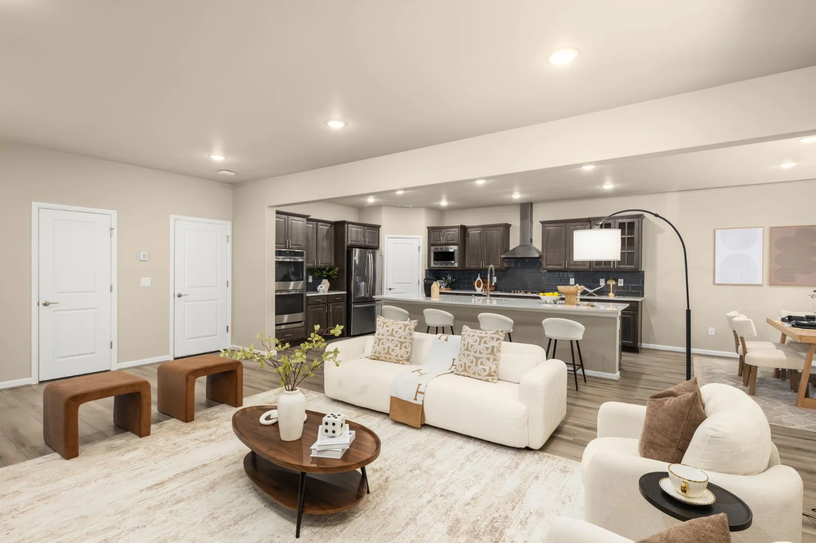 Open-plan living room with cream seating and warm wood accents beside a kitchen