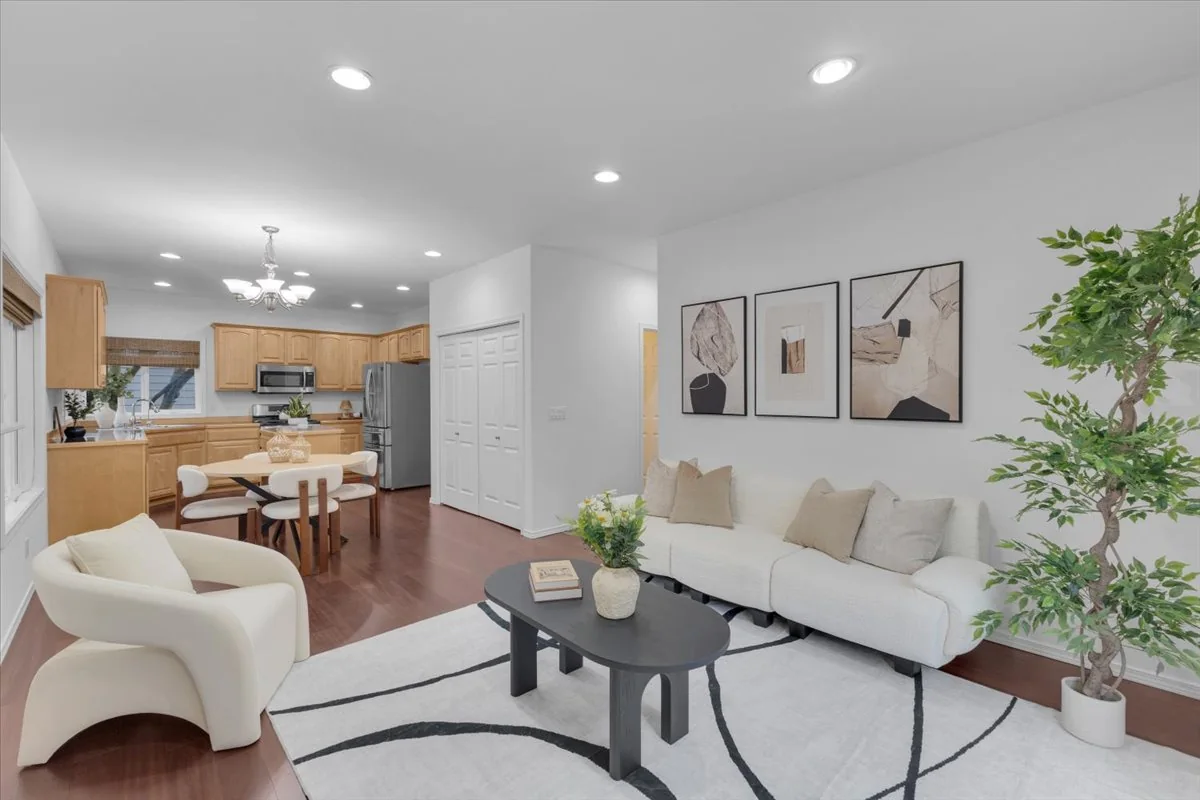 Living room with a white sofa, light armchairs, a dark coffee table, and a patterned rug