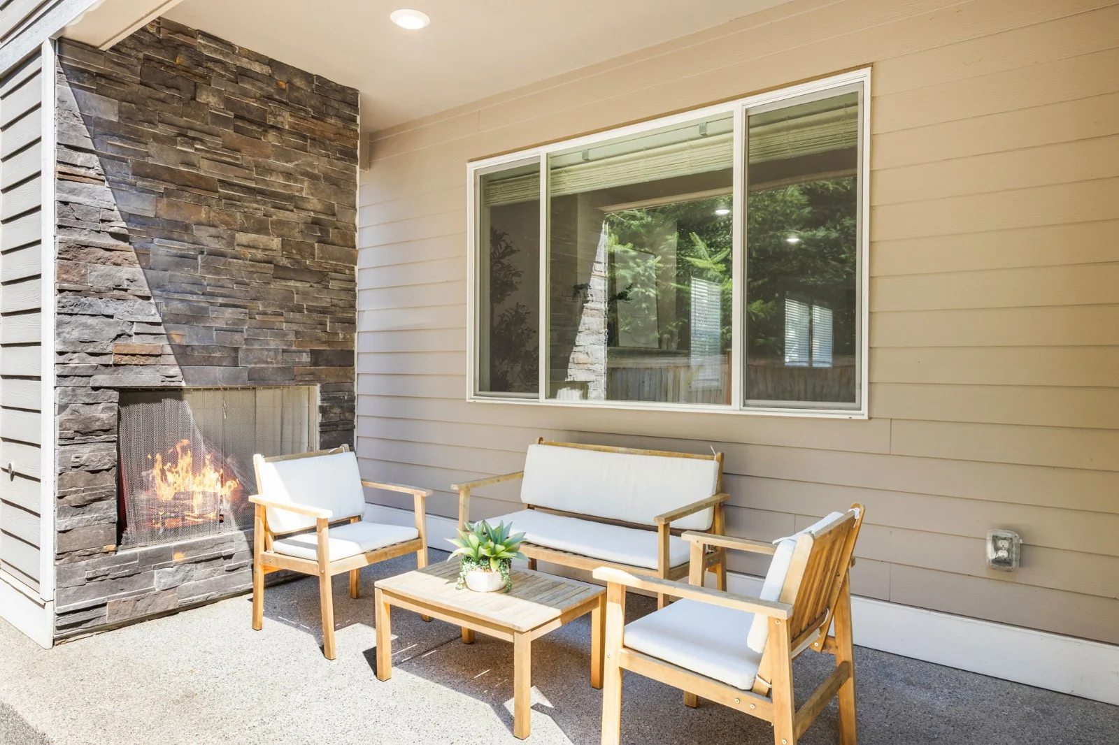 Covered patio with a stone fireplace, outdoor seating, and a low coffee table
